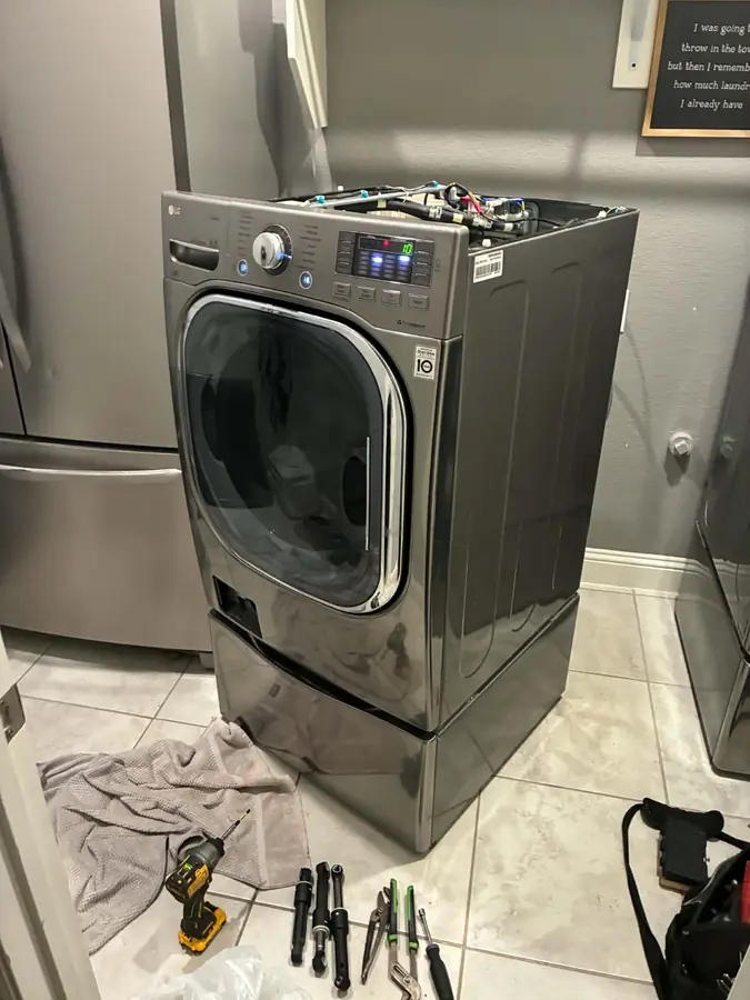 LG Front-Load Washer Suspension Repair: An LG front-loader on its pedestal, top panel off for a shock absorber replacement